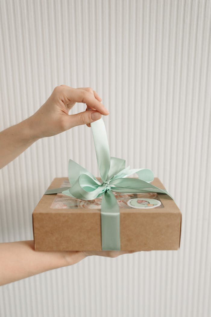 Crafting Captivating Headlines: Your awesome post title goes here Hand holding a decorative box with cupcakes inside, tied with a pastel ribbon.